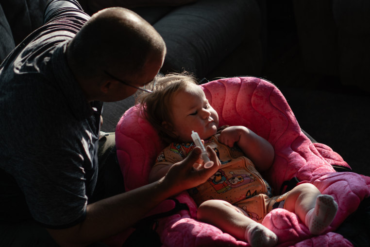 Patrick Lazoen feeds his daughter Emmalyn a bottle that contains her medicines.