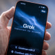A hand holds a smartphone with the Grok app opened on the screen