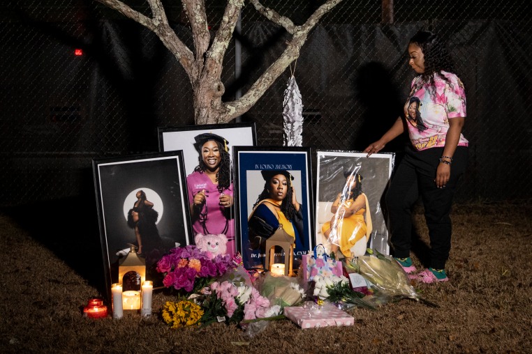 Selina Green, sister of Dr. Janell Green Smith, stands next to a collection of photos, flowers and candles arranged for her former sister, on Jan. 7, 2026, on Charleston. Smith was a former midwife and maternal rights advocate that died after giving birth to her own child.