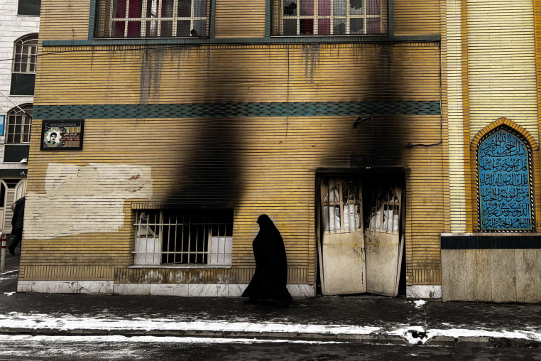 A woman passes a damaged mosque in Tehran on Jan. 21, 2026. Many mosques have Basij headquarters and were set on fire during protests.