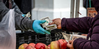 A shopper pays for produce at the farmer's market 