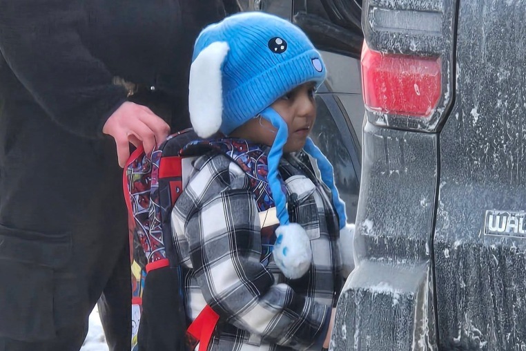Liam Conejo Ramos, wearing a blue hat, is led into a car