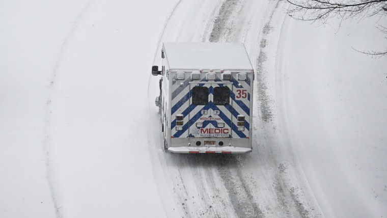 An ambulance drives on a road in a snowy landscape