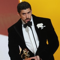 Bad Bunny on stage at the Grammys, wearing a tuxedo and holding an award.