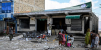 Local residents look at a damaged bank on the outskirts of Quetta on February 1, a day after an attack by Baloch separatists.
