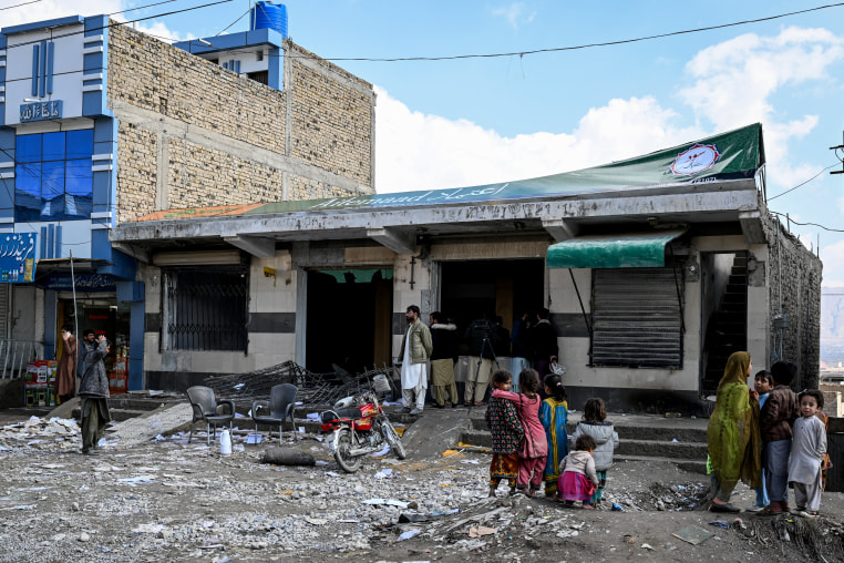 Local residents look at a damaged bank on the outskirts of Quetta on February 1, a day after an attack by Baloch separatists.